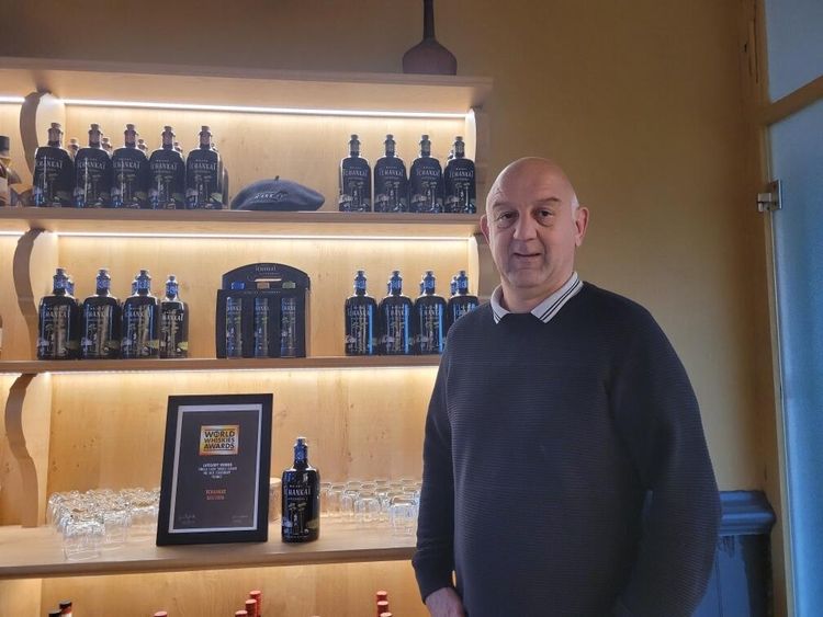 Marc Sucere, maître de chai, devant la vitrine de Tchankat avec le visuel du prix World Whiskies Awards